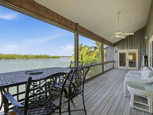 Wooden terrace with a ceiling fan, a sunroom, a water view, and french doors