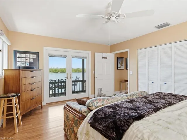 Bedroom featuring french doors, access to outside, light wood-style flooring, a ceiling fan, and a water view