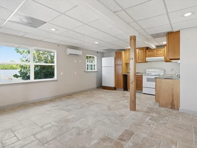 Kitchen with white appliances, brown cabinets, recessed lighting, under cabinet range hood, and a wall mounted air conditioner