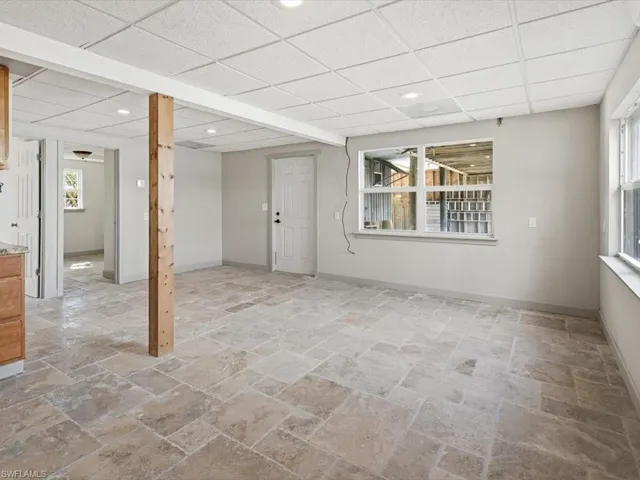 Below grade area featuring stone tile floors, recessed lighting, and a drop ceiling