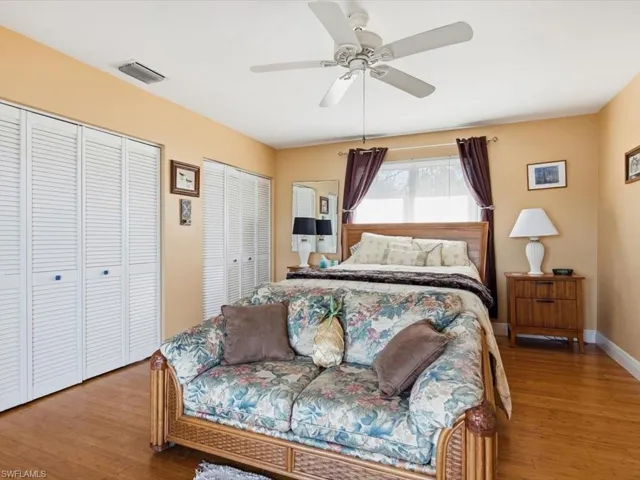 Bedroom with two closets, wood finished floors, and ceiling fan