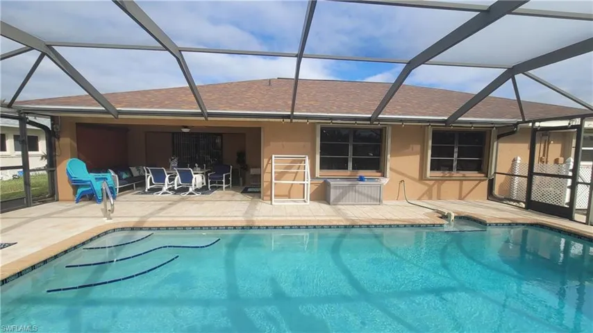 View of swimming pool featuring glass enclosure and a patio area