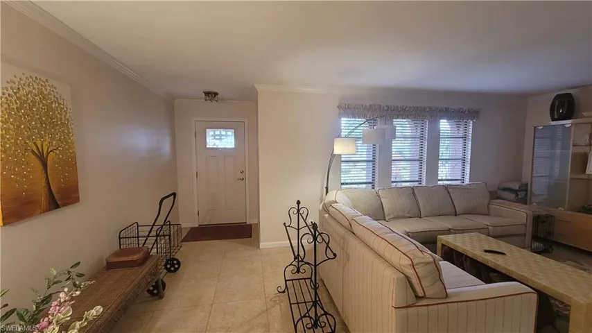 Living room featuring crown molding and light tile patterned flooring