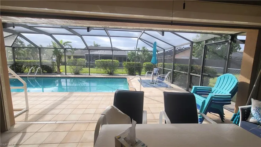 View of swimming pool featuring glass enclosure and a patio area