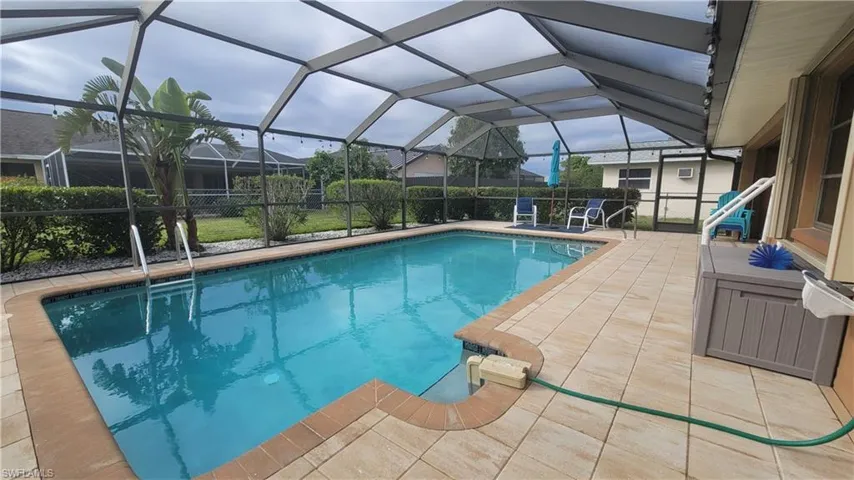 View of swimming pool with glass enclosure and a patio area