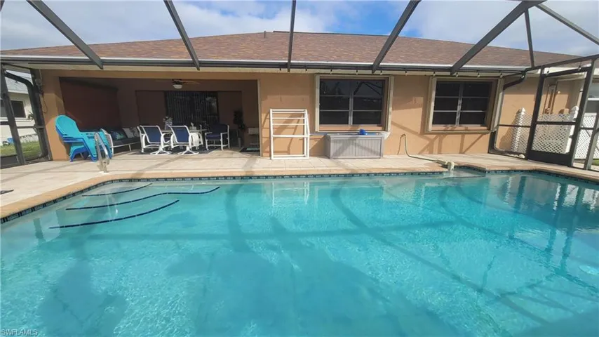 View of pool featuring glass enclosure, ceiling fan, and a patio
