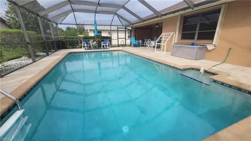 View of swimming pool with glass enclosure, ceiling fan, and a patio area