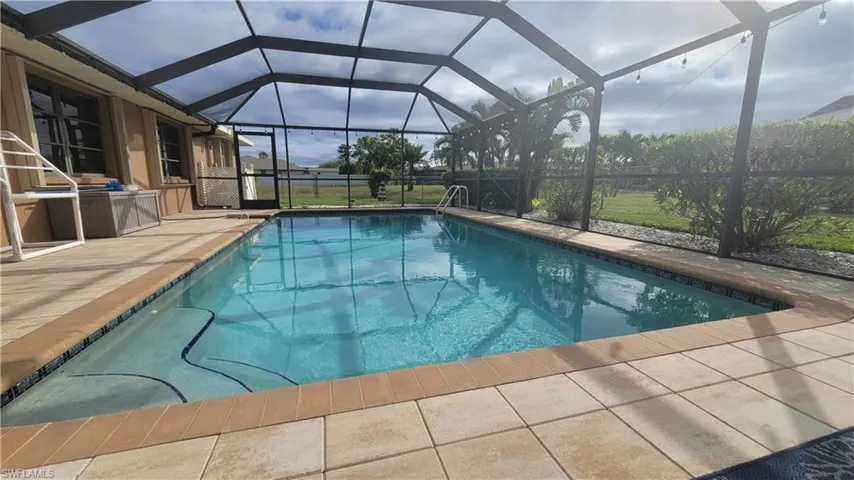 View of swimming pool with a patio and glass enclosure