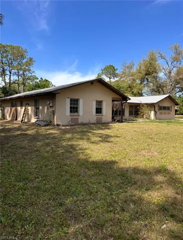 Rear view of property with a lawn and stucco siding