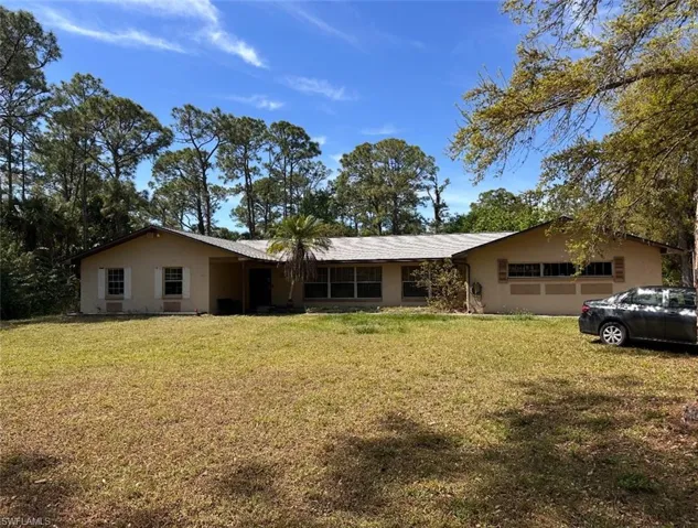 Single story home featuring an attached garage, stucco siding, and a front yard