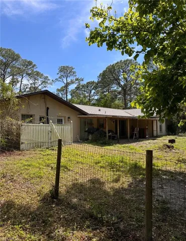 Rear view of house with fence and stucco siding