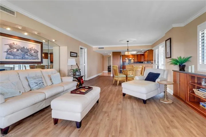 Living room featuring ornamental molding, light wood-style flooring, and baseboards