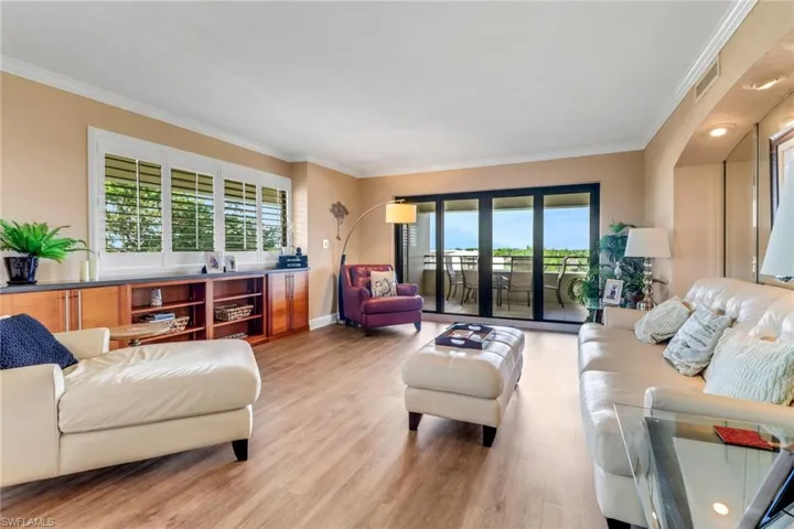 Living area with healthy amount of natural light, crown molding, light wood finished floors, and baseboards