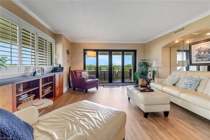 Living area featuring wood finished floors, ornamental molding, and healthy amount of natural light