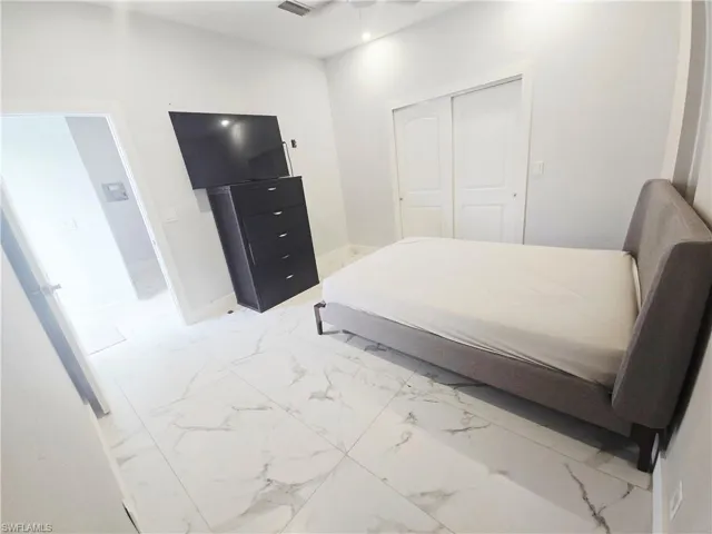 Mother-in-law Bedroom featuring light marble finish floors and a closet