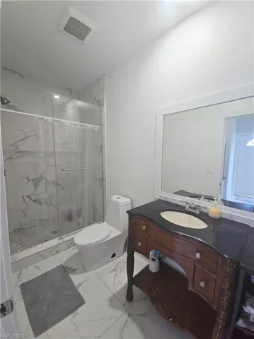 Mother-in-law Bathroom with vanity, a marble finish shower, and marble finish flooring