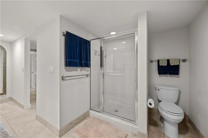 Bathroom with tile patterned floors, toilet, and a shower with door