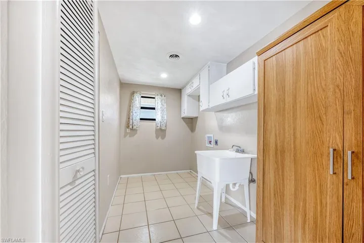 Clothes washing area featuring hookup for a washing machine and light tile patterned floors