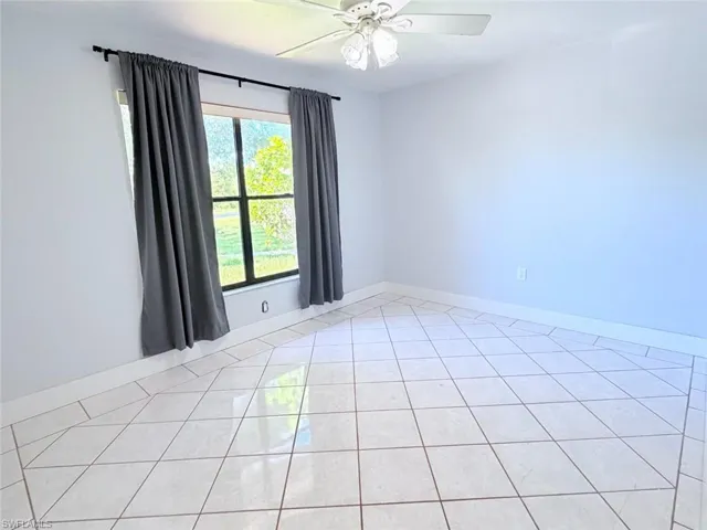 Ceramic tile flooring arranged in a diagonal pattern, large window with black framing, and a ceiling-mounted light fixture with a fan