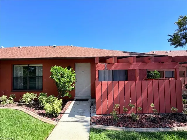 Exterior featuring a stucco facade, shingled roof, and a wooden privacy screen with an overhead pergola