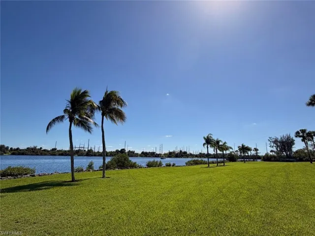 Waterfront parcel featuring extensive lawn space, mature palm trees, and direct water frontage
