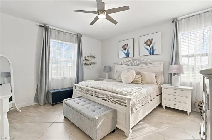Spacious primary bedroom with his and her walk-in closets, recessed lighting, ceiling fan, tiled flooring, and windows with white blinds