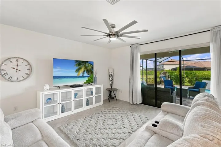 Living room open to dining and kitchen, with recessed lighting, large ceiling fan, and sliding glass door to outdoor living area