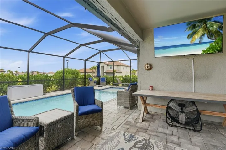 Screened-in outdoor living space with a custom pool, pavers, and exterior wall-mounted TV
