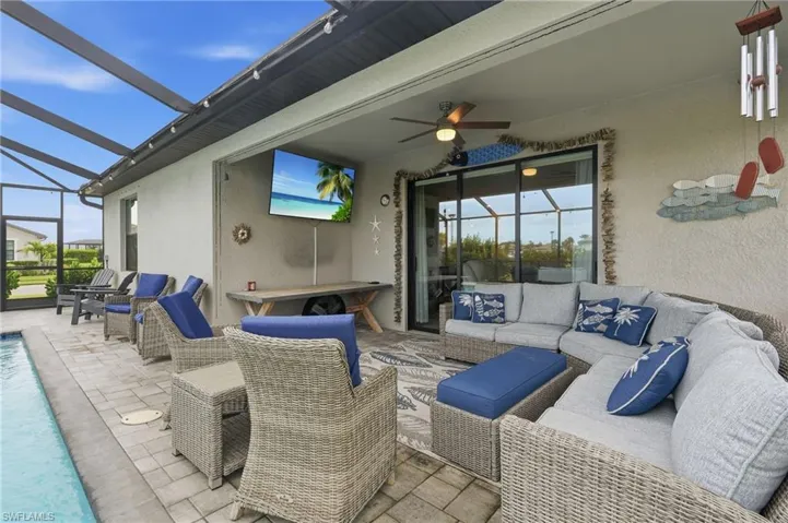 Screened-in outdoor living space with a custom pool, pavers, and exterior wall-mounted TV