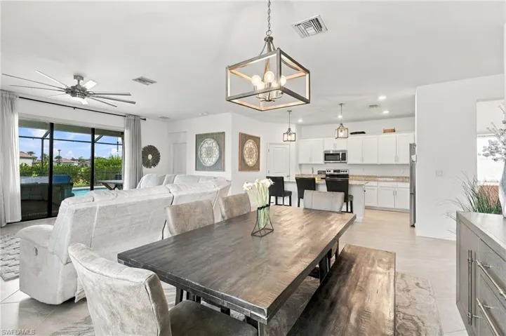 Open-concept living area with a contemporary chandelier, recessed lighting, a ceiling fan, and slider with automated shade