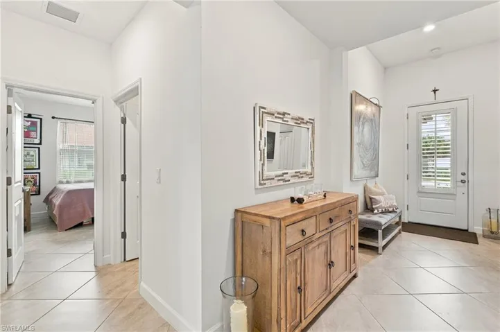 White interior walls, tile flooring, recessed lighting, and a white entry door with louvered glass inserts