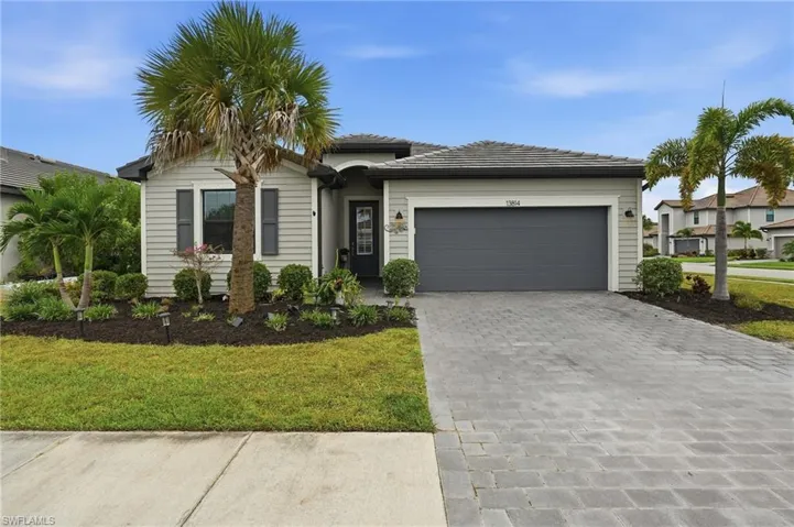 Single-story residence featuring light-colored siding, a dark garage door, and a paver driveway