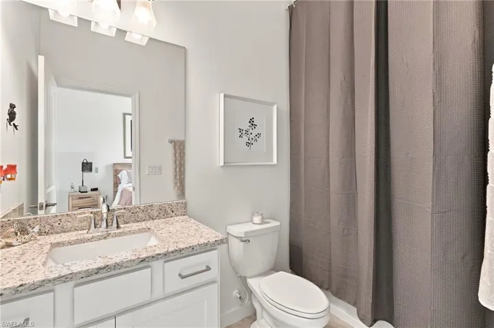 Junior ensuite bathroom with bathtub/shower, white vanity, granite countertop, undermount sink, polished chrome faucet