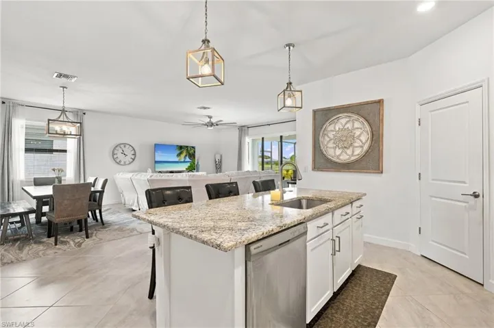 Kitchen featuring white cabinetry, granite, stainless steel appliances, a center island with bar seating, pendant lighting, and walk-in pantry