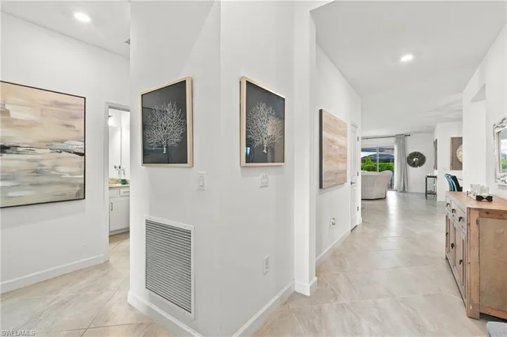 Recessed ceiling lighting illuminates the split hallway with large format tile flooring - two bedrooms and bathroom to the left and main living area straight ahead
