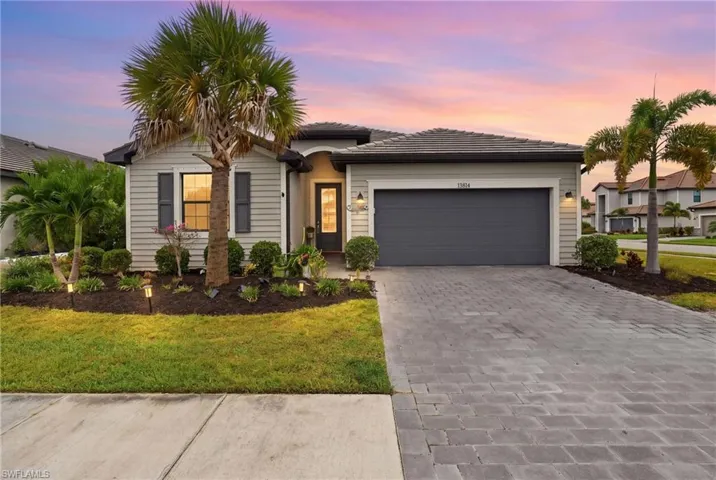 Single-story residence featuring horizontal siding, a paver driveway, an attached garage, and mature landscaping