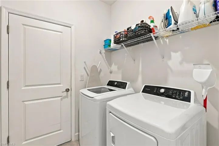 Laundry room featuring washer, driver, a wire storage shelf and tile flooring