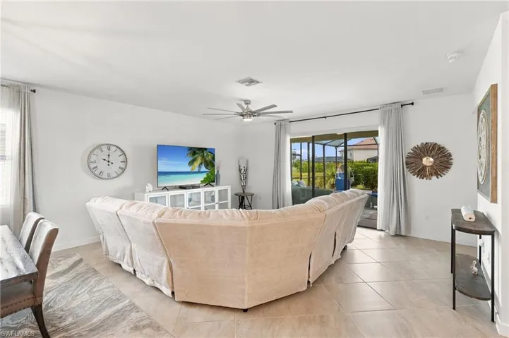 Living room open to dining and kitchen, with recessed lighting, large ceiling fan, and sliding glass door to outdoor living area