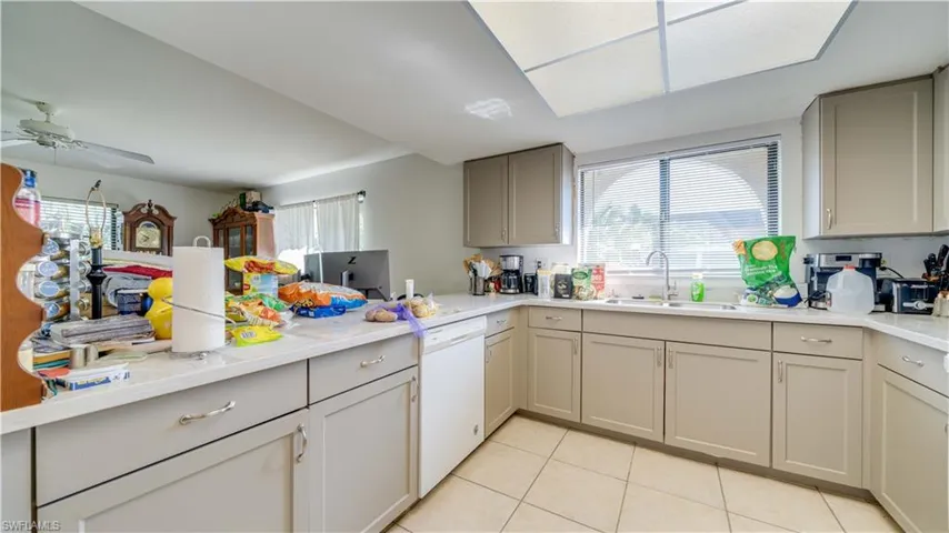 Unit 1 kitchen featuring light tile patterned floors, dishwasher, gray cabinets, a peninsula, and ceiling fan