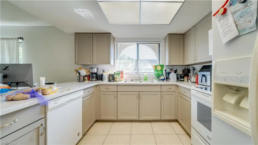 Unit 1 with updated kitchen featuring white appliances, light tile patterned floors, and gray cabinetry