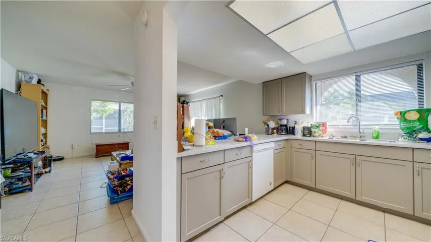 Unit 1 kitchen with gray cabinetry, light tile patterned floors, open floor plan, and white dishwasher