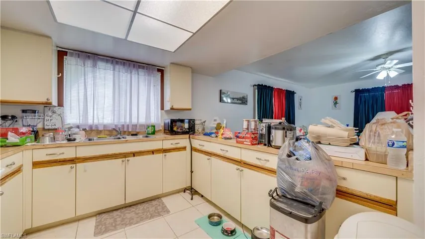 Kitchen featuring light tile patterned flooring, light countertops, black microwave, a peninsula, and cream cabinets