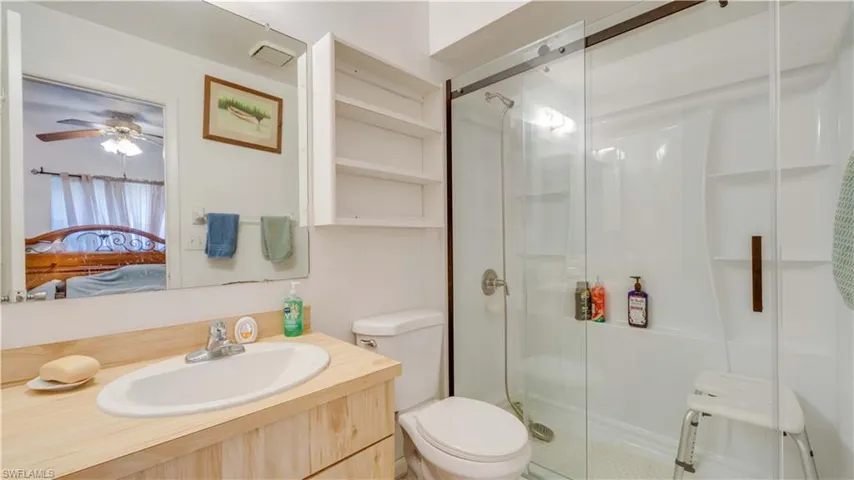 Ensuite bathroom featuring a stall shower, vanity, and a ceiling fan