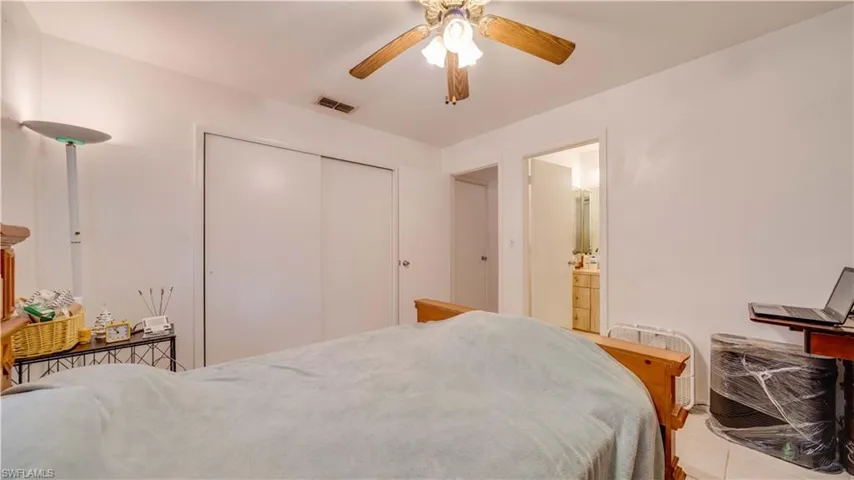 Tiled bedroom with a ceiling fan, a closet, and ensuite bathroom