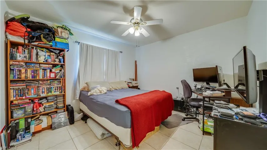 Bedroom with light tile patterned flooring, ceiling fan, and a desk