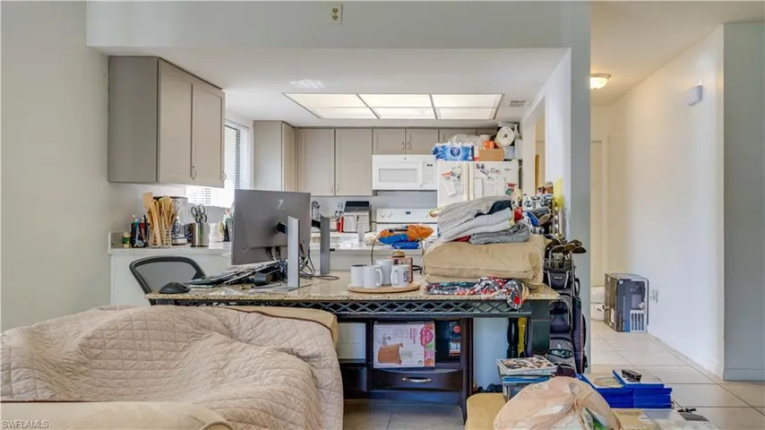 Kitchen with light tile patterned floors, white appliances, and light countertops