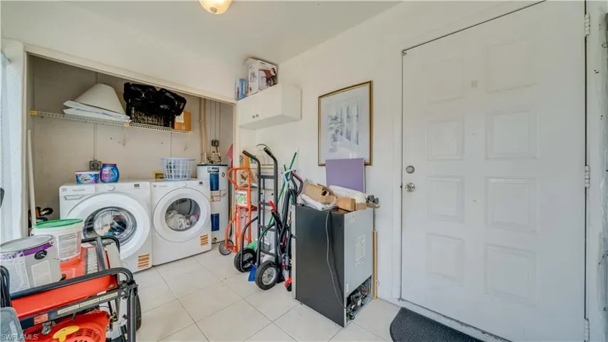 Washroom with light tile patterned floors, independent washer and dryer, and electric water heater