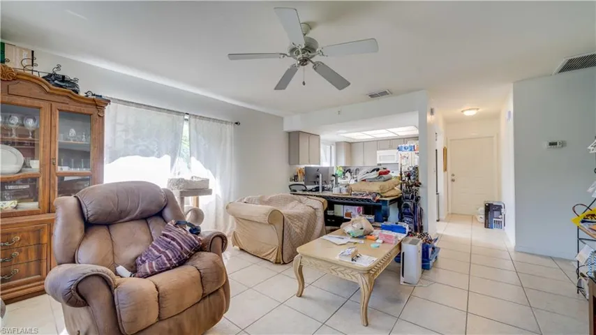 Living area featuring light tile patterned floors and a ceiling fan