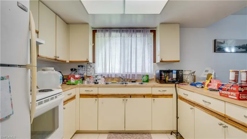 Kitchen featuring white appliances, cream cabinets, light countertops, and light tile patterned floors