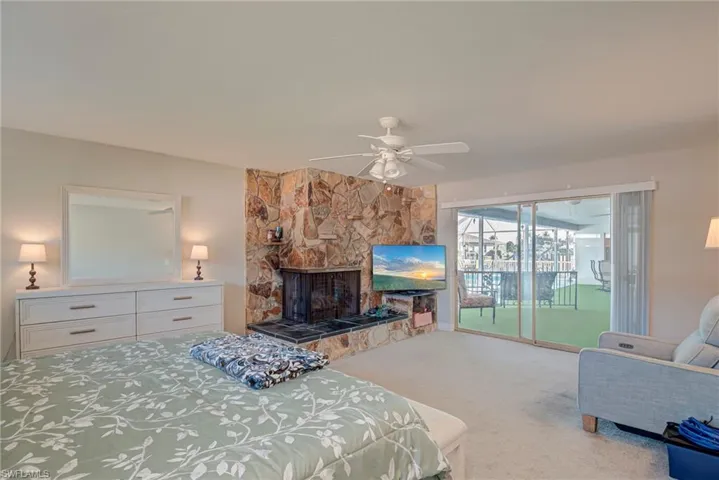 Bedroom featuring access to exterior, carpet floors, ceiling fan, and a fireplace